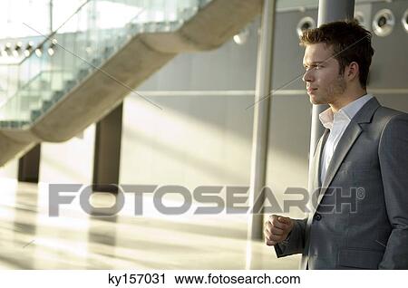 Businessman leaning against a pole View Large Photo Image Stock Image - Businessman leaning against a pole. Fotosearch