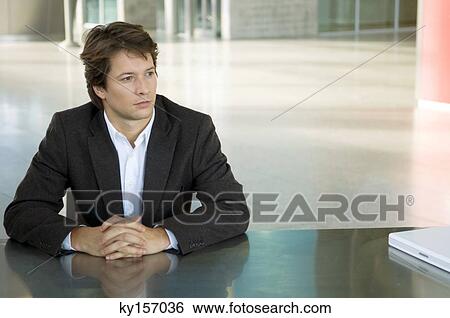 Businessman sitting at a desk with his hands clasped View Large Photo Image Stock Photograph - Businessman sitting at a desk with his hands clasped. Fotosearch
