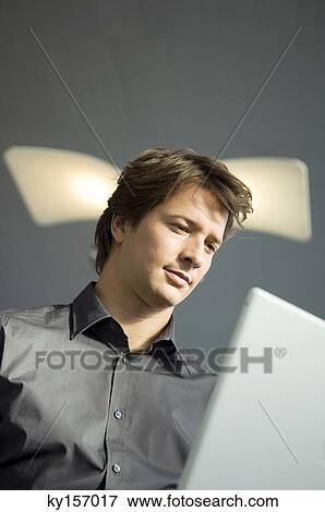 Low angle view of a businessman working on a laptop View Large Photo Image Stock Photo - Low angle view of a businessman working on a laptop. Fotosearch