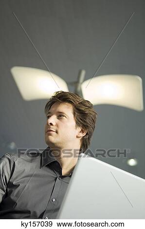 Low angle view of a businessman working on a laptop View Large Photo Image Stock Photo - Low angle view of a businessman working on a laptop. Fotosearch