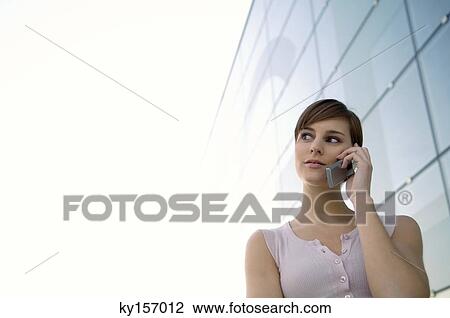 Low angle view of a young woman talking on a mobile phone View Large Photo Image Stock Image - Low angle view of a young woman talking on a mobile phone. Fotosearch