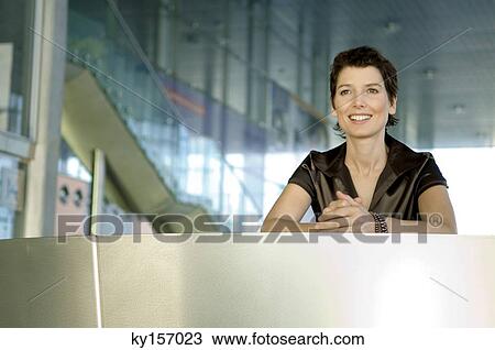 Stock Image - Mid adult woman at a hotel reception counter. Fotosearch