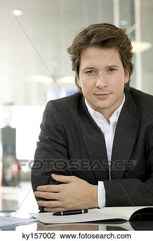 Portrait of a businessman sitting at a desk View Large Photo Image Stock Image - Portrait of a businessman sitting at a desk. Fotosearch