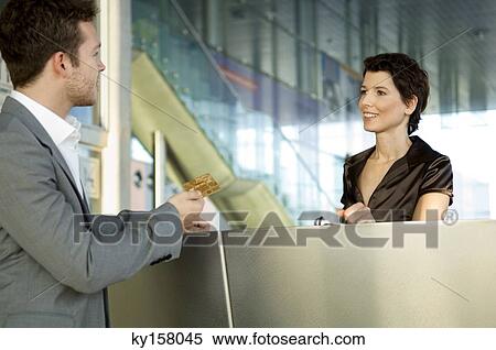 Businessman giving a credit card to a hotel receptionist View Large Photo Image Stock Photography - Businessman giving a credit card to a hotel receptionist. Fotosearch