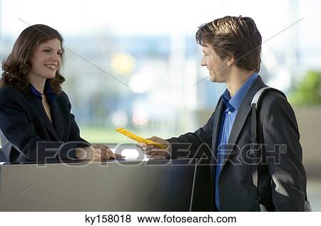 Businessman holding a bill and talking to a receptionist View Large Photo Image Stock Photo - Businessman holding a bill and talking to a receptionist. Fotosearch