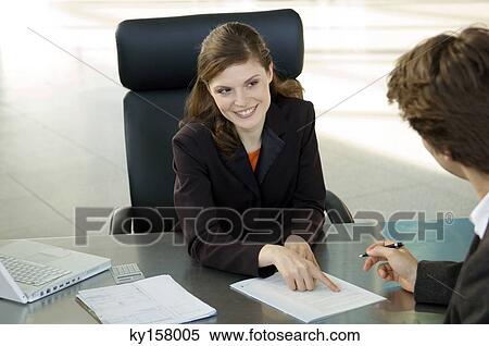 Businesswoman pointing at a contract and businessman sitting in front of her View Large Photo Image Stock Photography - Businesswoman pointing at a contract and businessman sitting in front of her. Fotosearch