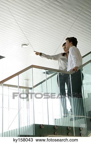 Businesswoman standing with a businessman and pointing forward View Large Photo Image Stock Image - Businesswoman standing with a businessman and pointing forward. Fotosearch