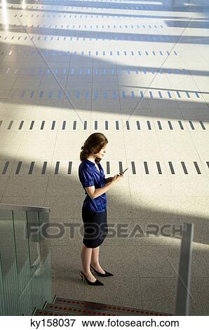 Businesswoman text messaging with a mobile phone View Large Photo Image Stock Photo - Businesswoman text messaging with a mobile phone. Fotosearch