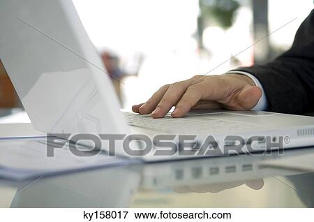 Stock Photo - Close-up of a businessman's hand using a laptop. Fotosearch