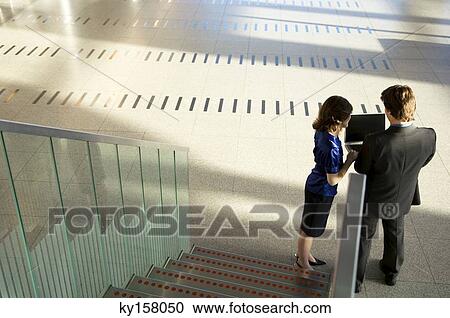 High angle view of a businessman and a businesswoman using a laptop View Large Photo Image Stock Image - High angle view of a businessman and a businesswoman using a laptop. Fotosearch