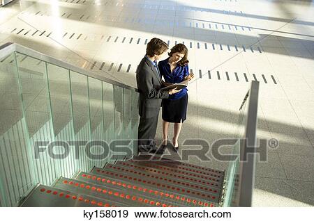 Stock Photo - High angle view of a businessman and a businesswoman looking at a diary. Fotosearch