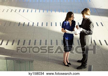 High angle view of a businesswoman showing a document to a businessman View Large Photo Image Picture - High angle view of a businesswoman showing a document to a businessman. Fotosearch