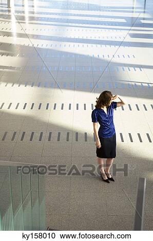 Stock Image - High angle view of a businesswoman shielding her eyes. Fotosearch