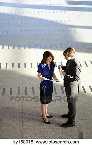 Stock Photography - High angle view of a businesswoman showing a document to a businessman. Fotosearch