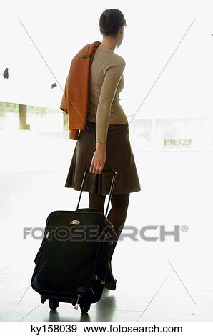 Rear view of a businesswoman pulling her luggage at an airport View Large Photo Image Stock Photo - Rear view of a businesswoman pulling her luggage at an airport. Fotosearch