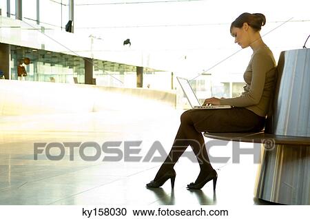Side profile of a businesswoman using a laptop at an airport lounge View Large Photo Image Stock Image - Side profile of a businesswoman using a laptop at an airport lounge. Fotosearch