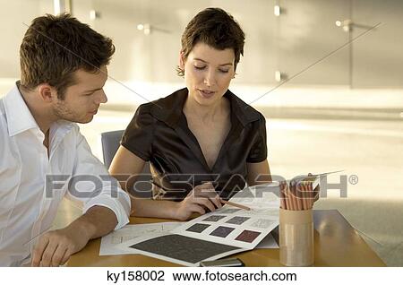 Stock Image - Two interior designers discussing on a color swatch. Fotosearch