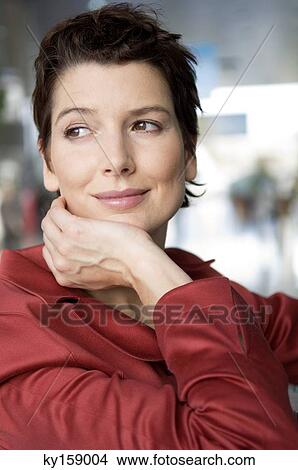 Close-up of a mid adult woman smiling with her hand on her chin View Large Photo Image Picture - Close-up of a mid adult woman smiling with her hand on her chin. Fotosearch