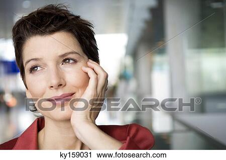 Close-up of a mid adult woman smiling with her hand on her chin View Large Photo Image Stock Image - Close-up of a mid adult woman smiling with her hand on her chin. Fotosearch