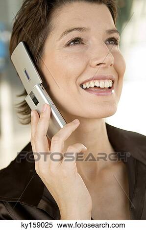 Close-up of a mid adult woman talking on a mobile phone View Large Photo Image Stock Photography - Close-up of a mid adult woman talking on a mobile phone. Fotosearch