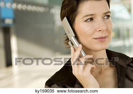 Close-up of a mid adult woman talking on a mobile phone View Large Photo Image Stock Photography - Close-up of a mid adult woman talking on a mobile phone. Fotosearch