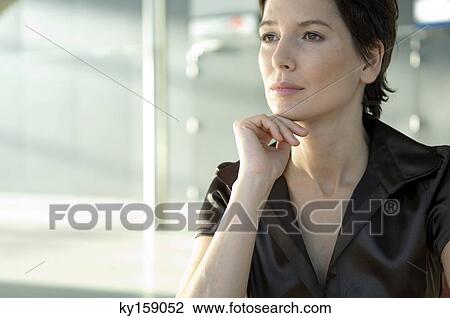 Close-up of a mid adult woman thinking with her hand on her chin View Large Photo Image Stock Image - Close-up of a mid adult woman thinking with her hand on her chin. Fotosearch