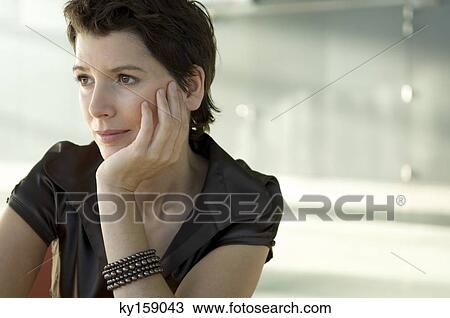 Close-up of a mid adult woman with her hand on her chin View Large Photo Image Stock Image - Close-up of a mid adult woman with her hand on her chin. Fotosearch