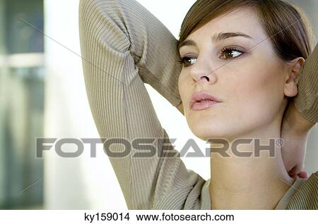 Picture - Close-up of a young woman with her hands behind her head. Fotosearch