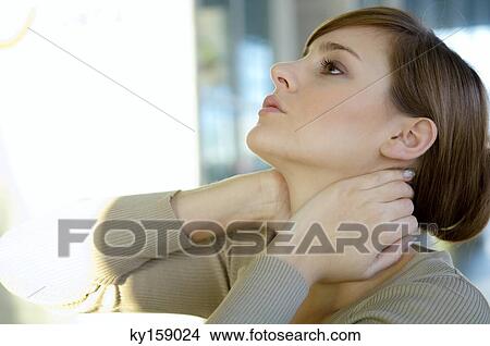 Close-up of a young woman with her hands on her neck View Large Photo Image Picture - Close-up of a young woman with her hands on her neck. Fotosearch