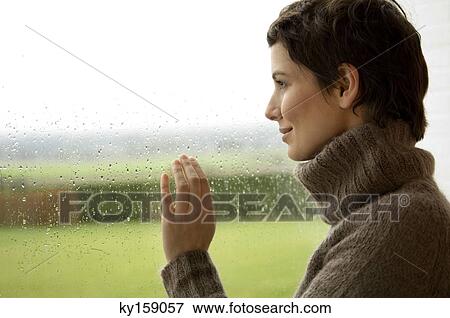 Mid adult woman looking out through a window View Large Photo Image Stock Photo - Mid adult woman looking out through a window. Fotosearch