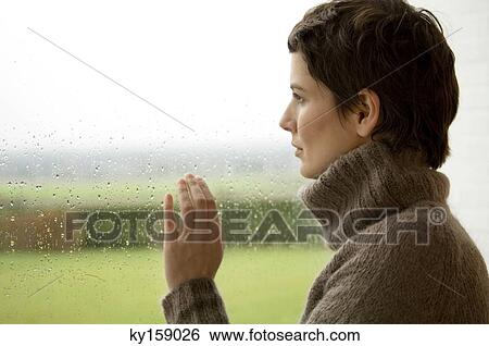 Mid adult woman looking out through a window View Large Photo Image Stock Photograph - Mid adult woman looking out through a window. Fotosearch