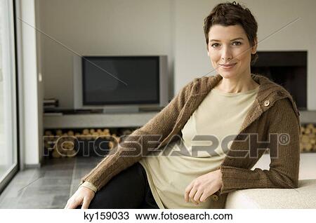 Portrait of a mid adult woman leaning against a couch View Large Photo Image Stock Image - Portrait of a mid adult woman leaning against a couch. Fotosearch