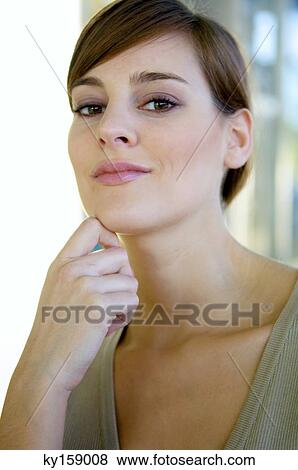 Stock Photo - Portrait of a young woman with her hand on her chin. Fotosearch