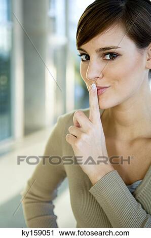 Portrait of a young woman with her finger on her lips View Large Photo Image Stock Image - Portrait of a young woman with her finger on her lips. Fotosearch