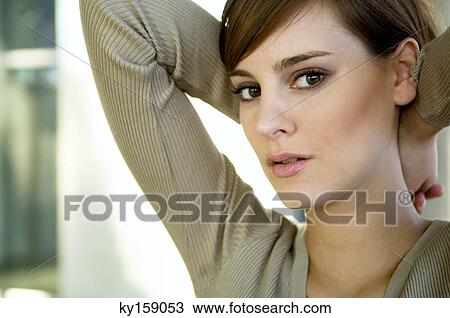 Portrait of a young woman with her hands behind her head View Large Photo Image Stock Image - Portrait of a young woman with her hands behind her head. Fotosearch