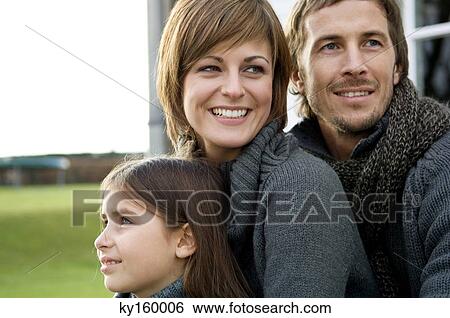 Close-up of a girl looking away with her parents smiling View Large Photo Image Stock Photograph - Close-up of a girl looking away with her parents smiling. Fotosearch