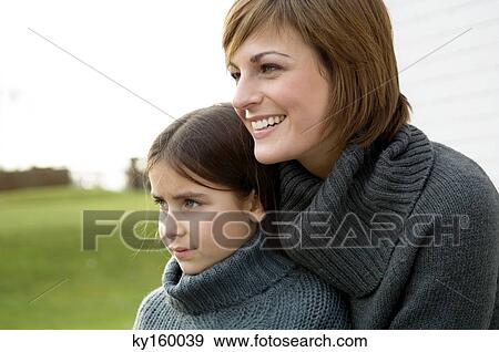 Close-up of a young woman hugging her daughter and smiling View Large Photo Image Stock Photo - Close-up of a young woman hugging her daughter and smiling. Fotosearch