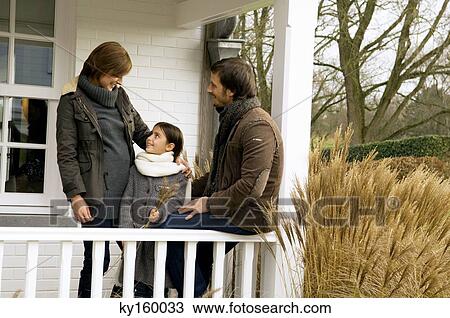 Stock Image - Girl standing and smiling with her parents in a balcony. Fotosearch