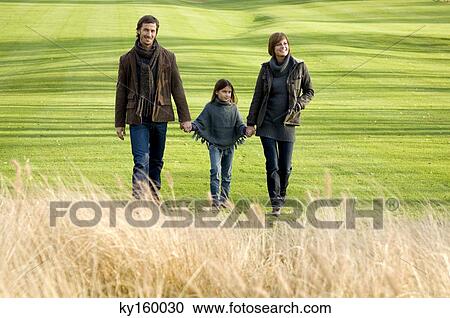 Girl with her parents walking in a park View Large Photo Image Stock Image - Girl with her parents walking in a park. Fotosearch