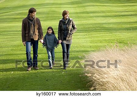 Stock Photo - Girl with her parents walking in a park. Fotosearch