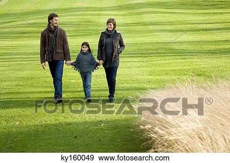 Girl with her parents walking in a park View Large Photo Image Stock Photo - Girl with her parents walking in a park. Fotosearch