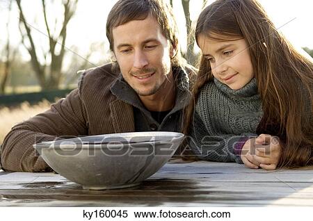 Mid adult man with his daughter looking into a bowl of water View Large Photo Image Stock Photography - Mid adult man with his daughter looking into a bowl of water. Fotosearch