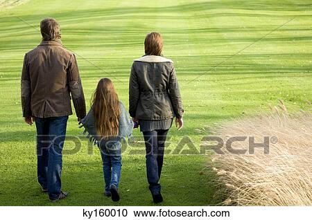 Rear view of a girl walking with her parents in a park View Large Photo Image Stock Image - Rear view of a girl walking with her parents in a park. Fotosearch