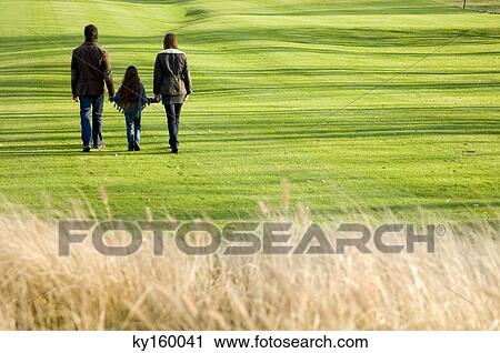 Rear view of a girl walking with her parents in a park View Large Photo Image Stock Image - Rear view of a girl walking with her parents in a park. Fotosearch