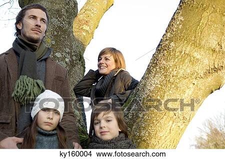 Two children standing near a tree with their parents View Large Photo Image Picture - Two children standing near a tree with their parents. Fotosearch
