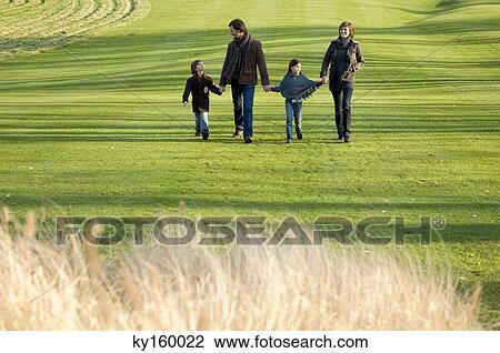 Two children with their parents walking in a park View Large Photo Image Stock Image - Two children with their parents walking in a park. Fotosearch