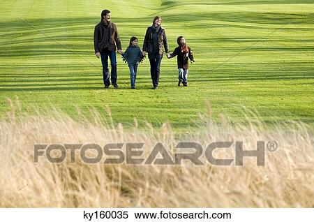 Two children with their parents walking in a park View Large Photo Image Stock Photography - Two children with their parents walking in a park. Fotosearch