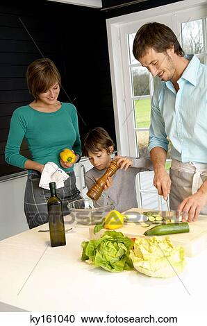 Mid adult man and a young woman preparing food with their son in a kitchen View Large Photo Image Stock Image - Mid adult man and a young woman preparing food with their son in a kitchen. Fotosearch