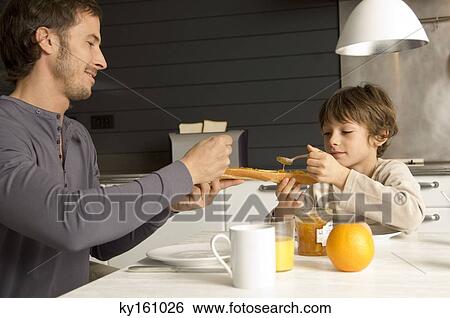 Mid adult man and his son having breakfast View Large Photo Image Stock Photograph - Mid adult man and his son having breakfast. Fotosearch