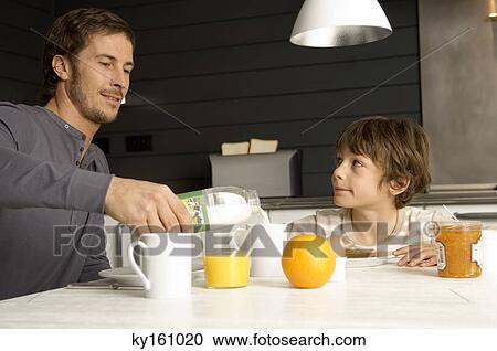 Mid adult man having breakfast with his son in the kitchen View Large Photo Image Stock Image - Mid adult man having breakfast with his son in the kitchen. Fotosearch